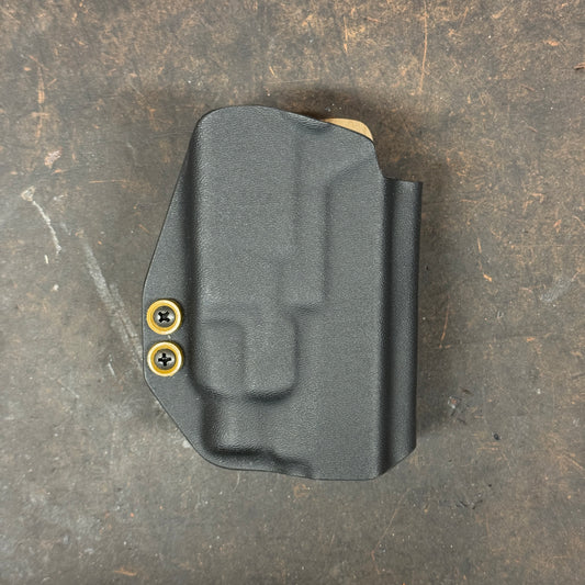 Black gun holster with FDE fasteners on a dark textured surface