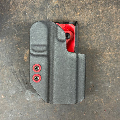 Gray gun holster with red accents on a textured surface